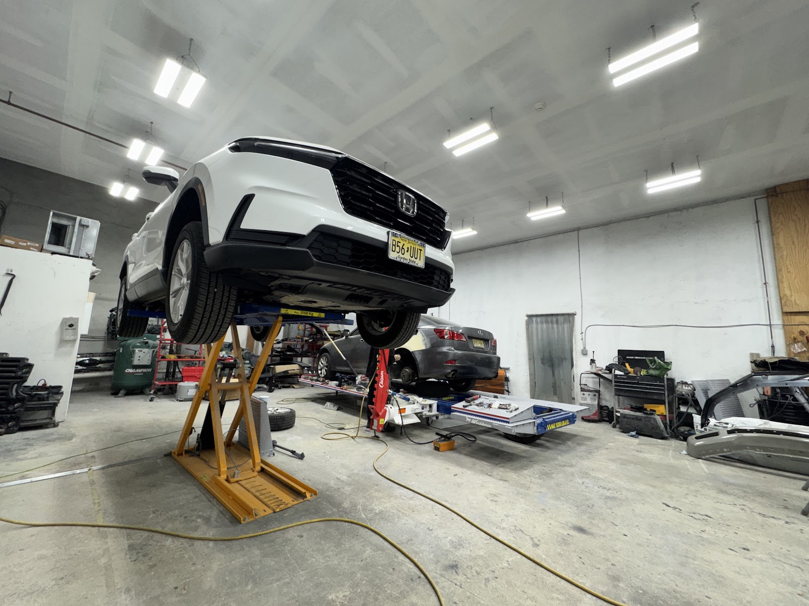 White Honda SUV on a lift inside Impact Pros' shop